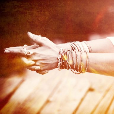 woman hands in yoga symbolic gesture mudra  lot of bracelets and rings  mix with textures closeup